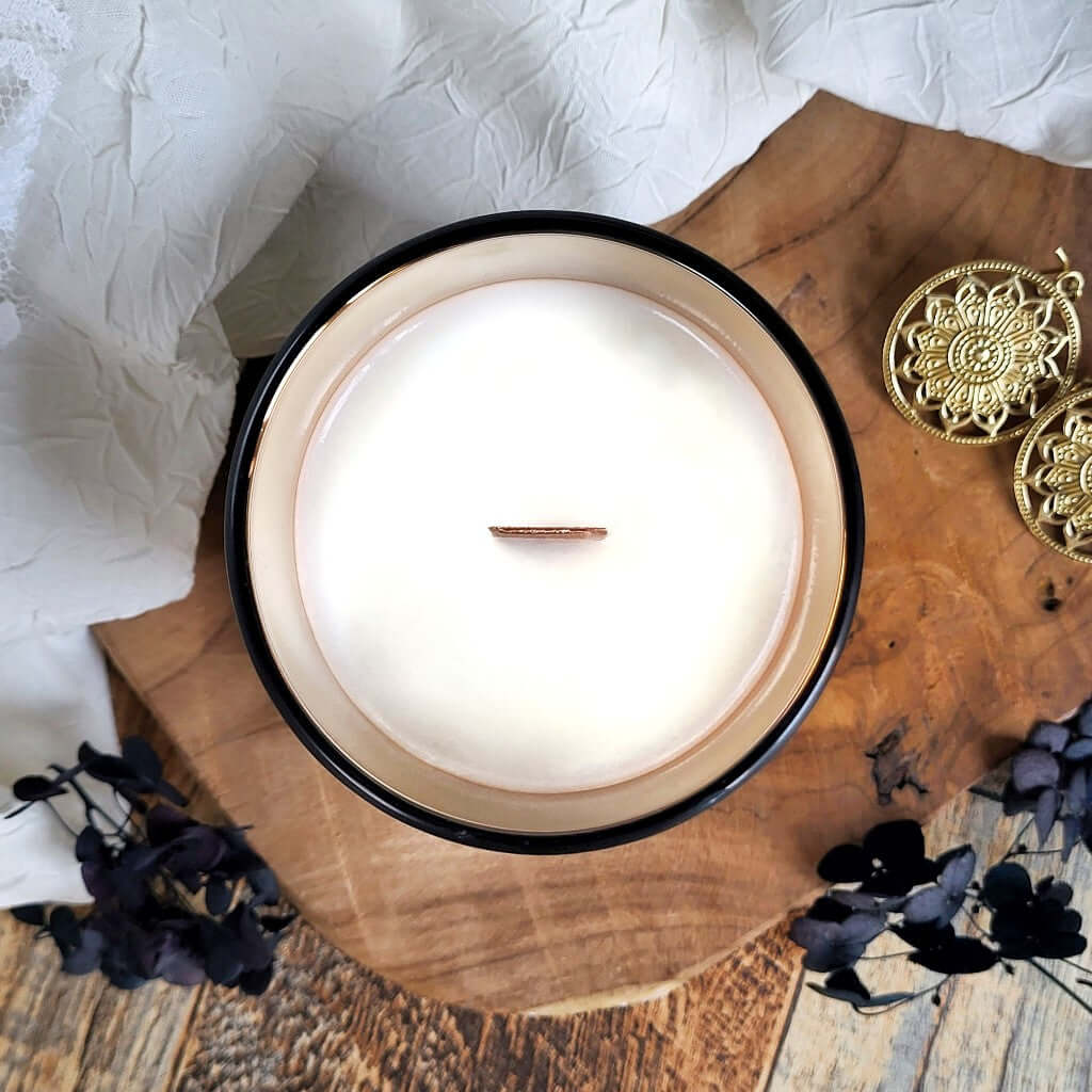 Candela profumata di lusso in cera di soia naturale. Realizzata in contenitore nero corvino e oro specchio con stoppino in legno. Design minimal e ricercato.