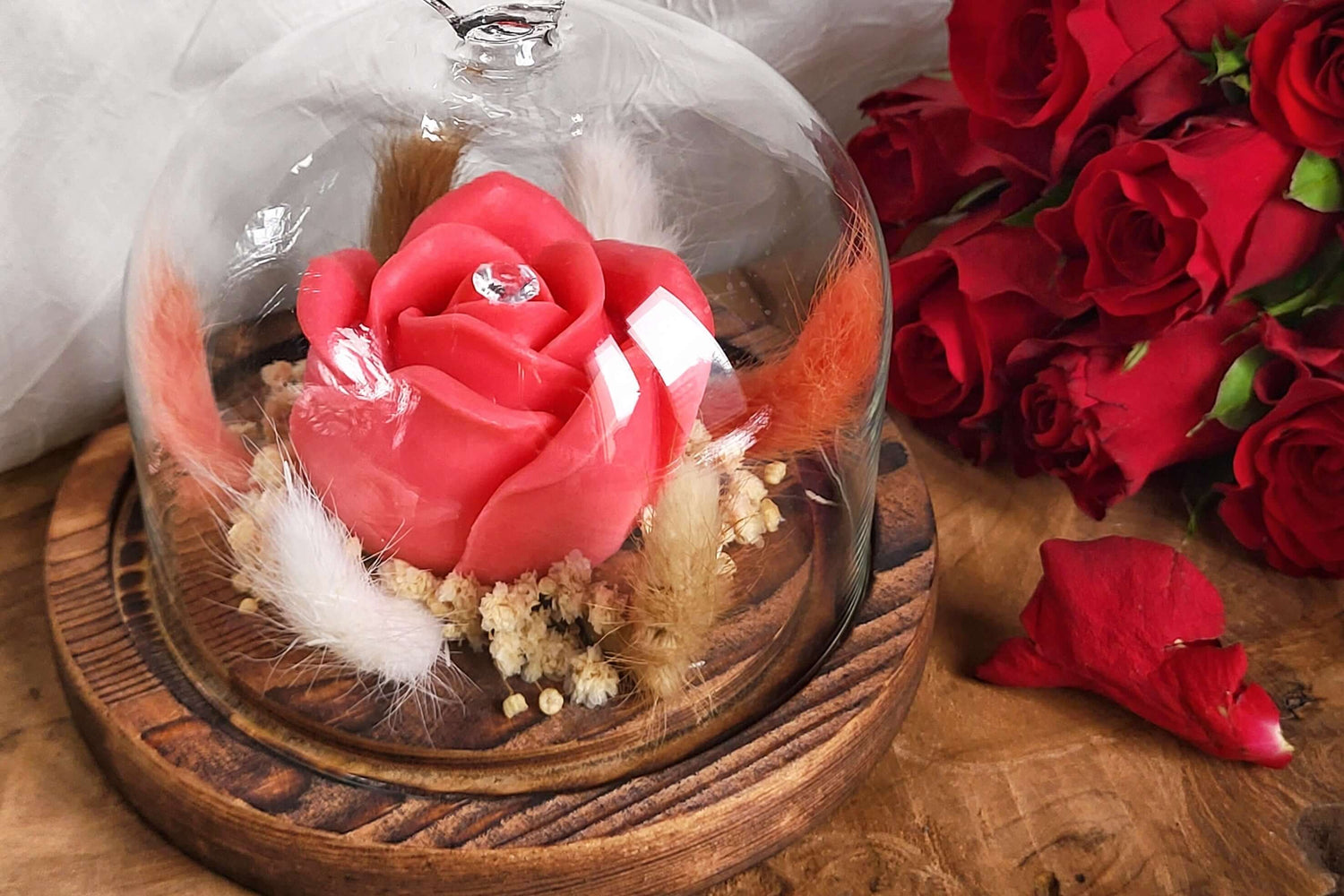 Candela profumata in cera di soia a forma di rosa con al centro un diamante. È realizzata in stile bouquet, con decorazioni pampas e fiori da sposa, all'interno di una campana in vetro trasparente con cuore e base in legno. Idea Regalo San Valentino 