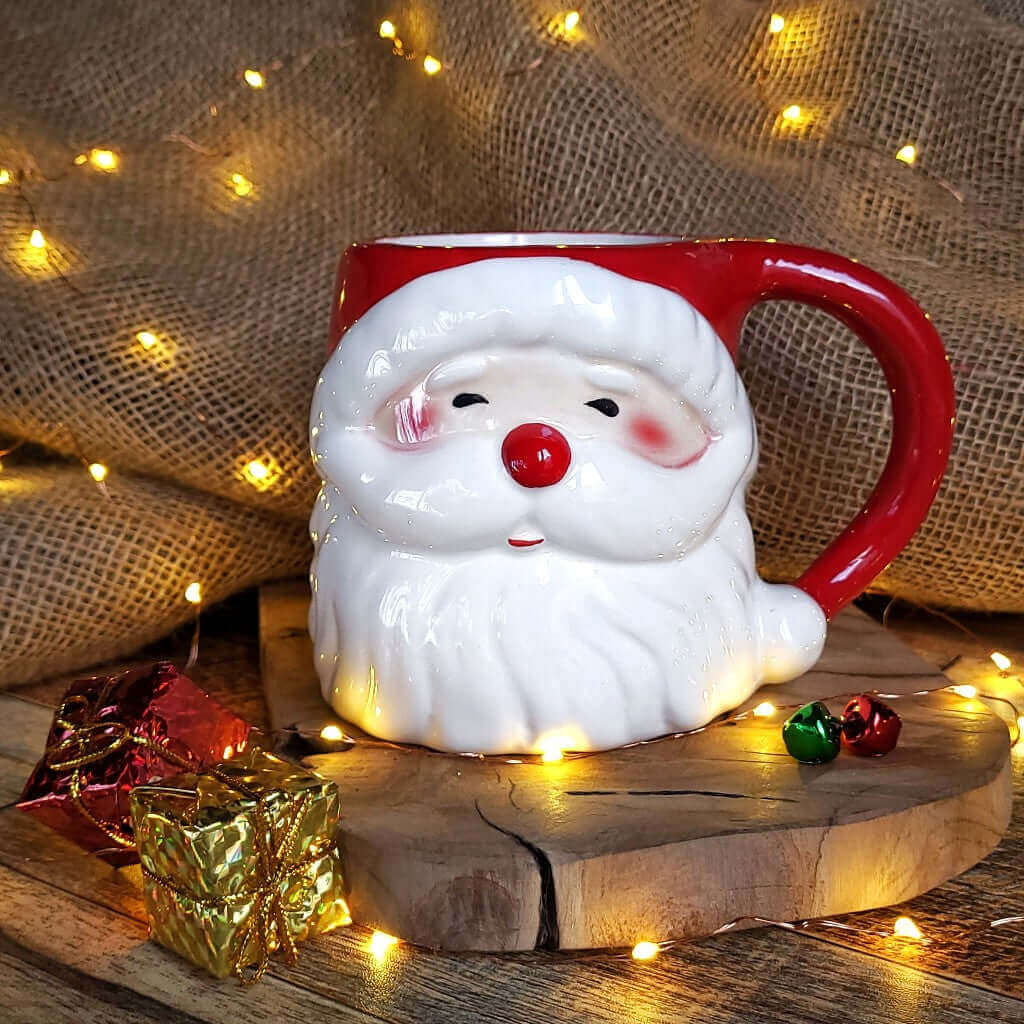 Tazza in ceramica a forma di pupazzo di Babbo Natale, più luci natalizie dorate.