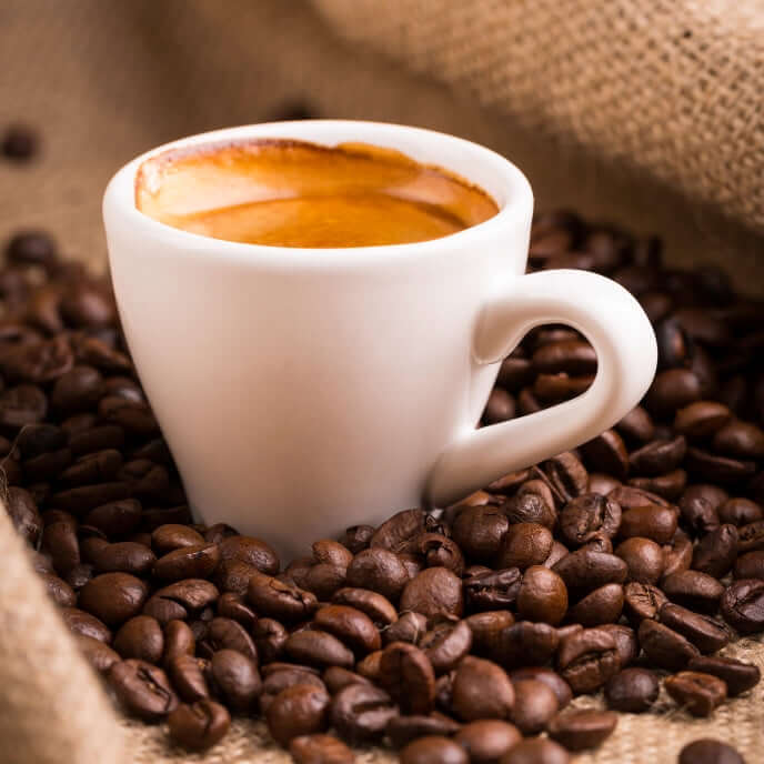 Tazzina e chicchi di caffè per indicare una fragranza per candele profumate dal nome Caffè Espresso. Materia prima con liquirizia, caffè, vaniglia, caramello come Note Olfattive.
