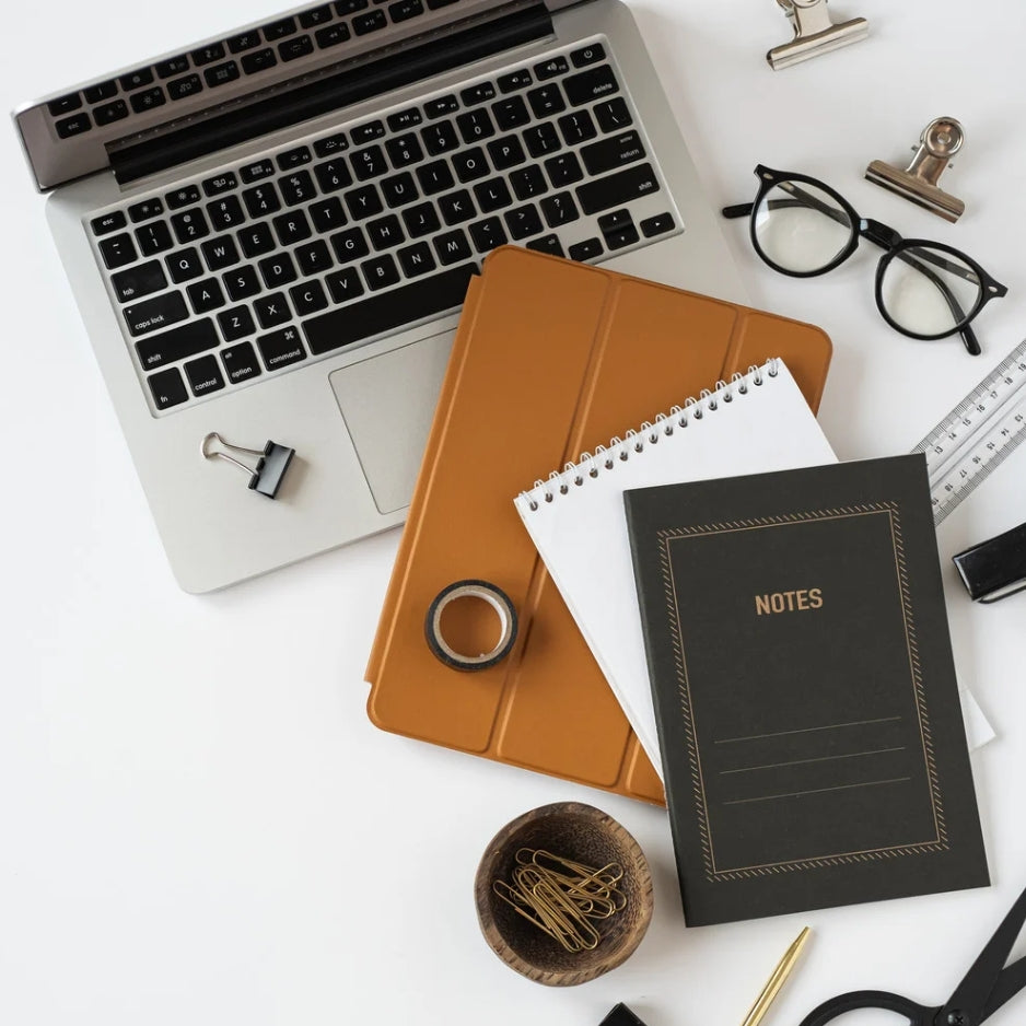 Il Faro: Consulenza One-to-One de Il Tempio Creativo per hobbiste, creative, artigiane e candle maker. In foto un notebook grigio con block notes, occhiali da vista neri, righello e clipse.