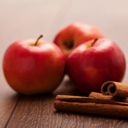 Tre mele rosse golden insieme a delle stecche di cannella, per indicare la fragranza per candele Mela e Cannella.