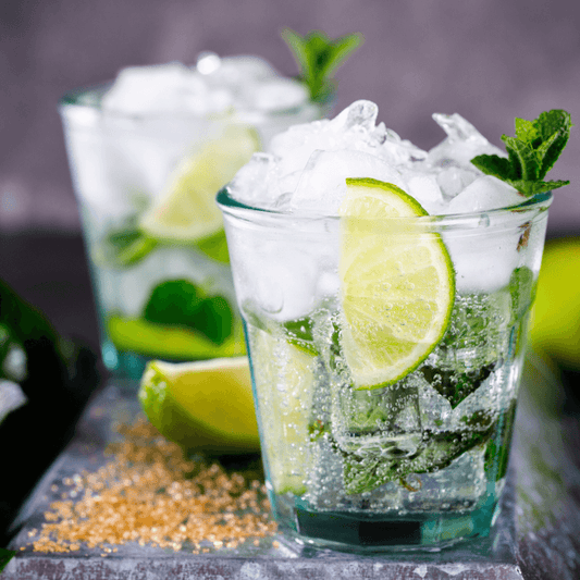 Bicchiere di vetro con al suo interno il cocktail Mojito con ghiaccio, line, menta e rum. Qui per indicare una fragranza per candele profumate.
