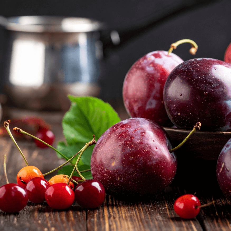 Grappoli di ciliegie con prugne rosse succose per indicare una fragranza per candele profumate.