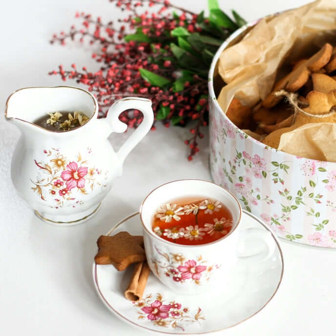Tazza da tea con biscotti natalizi per indicare una fragranza per candele profumate dal nome Tea e Pan di Zenzero. Ha arancia, zenzero, cannella, cocco come Note Olfattive.