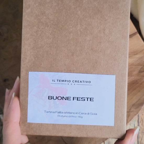 Tartina Profuma Armadi e Cassetti in cera di soia naturale al profumo di Pino. È a forma di Albero di Natale e Decorata con campanellino rosso. Scritta Merry di Merry Christmas. Qui il packaging in cartone kraft.